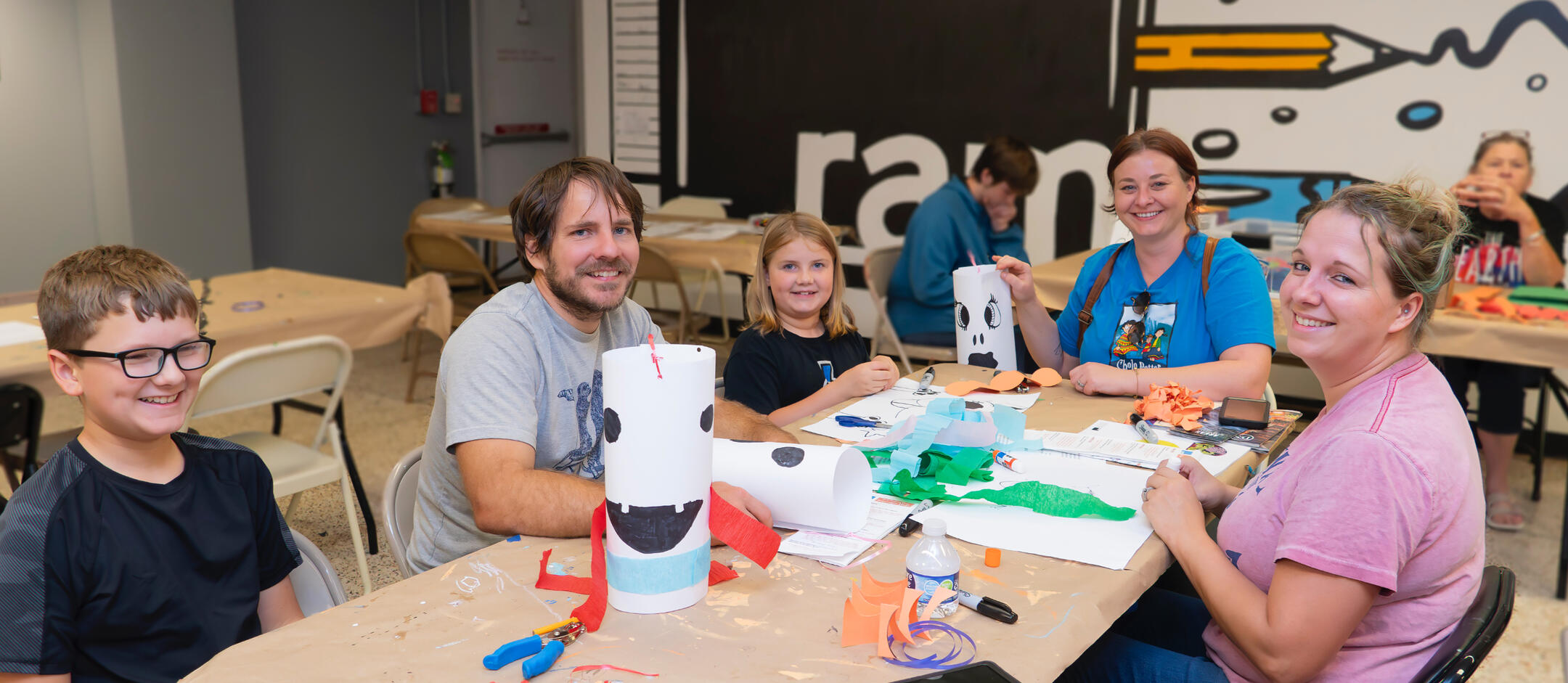 Family smiling while creating a craft inside the Fort Smith Regional Art Museum